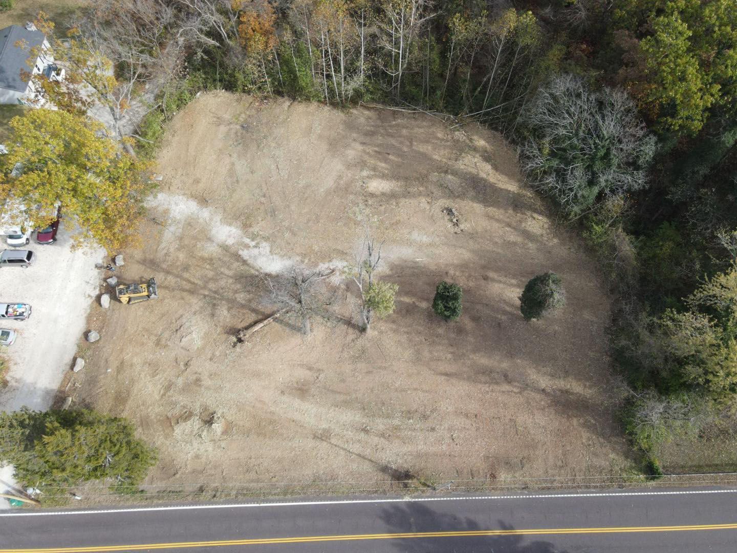 Excavator clearing brush in a grassy field